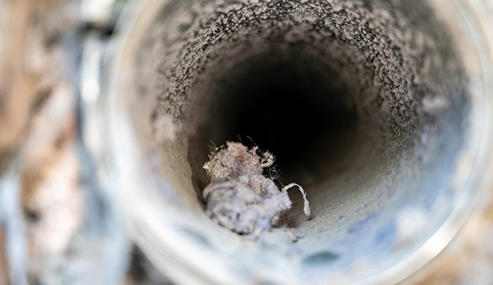 Close-up view of the interior of a dirty air duct with dust and debris.