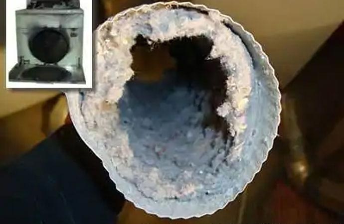 A close-up view of a dryer vent heavily clogged with lint and debris.