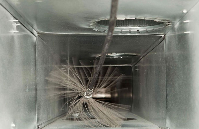 A close-up view of a duct cleaning brush inside an air duct.