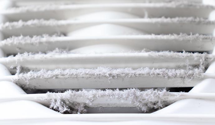 Close-up of an extremely dirty and dusty white plastic ventilation air grille at home.
