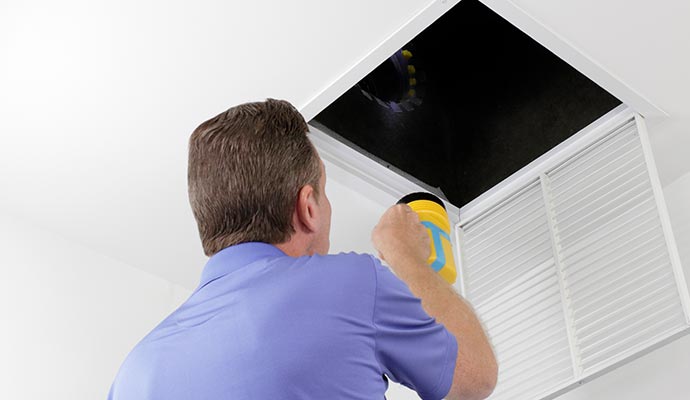 professional worker inspecting air duct