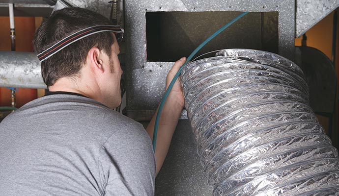 Technician installing air duct after cleaning it.